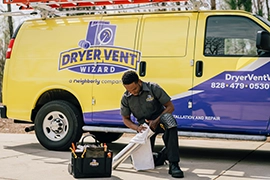 Technician kneeling in front of van.